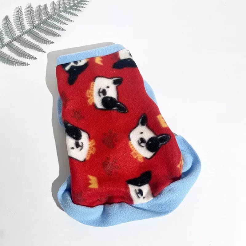 Cozy fleece jacket for pooches in red with a charming blue trim and a playful pattern of white and black sheepdog faces.