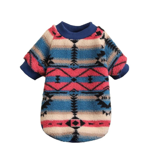 This image features a vibrant and colorful cozy tribal dog sweater, showcasing an intricate pattern with a mix of pink, blue, beige, and black hues.