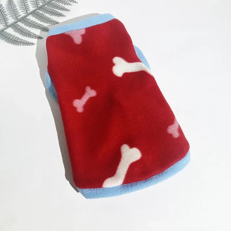 A red fleece jacket for pooches with white bone patterns, blue trim, and a soft.